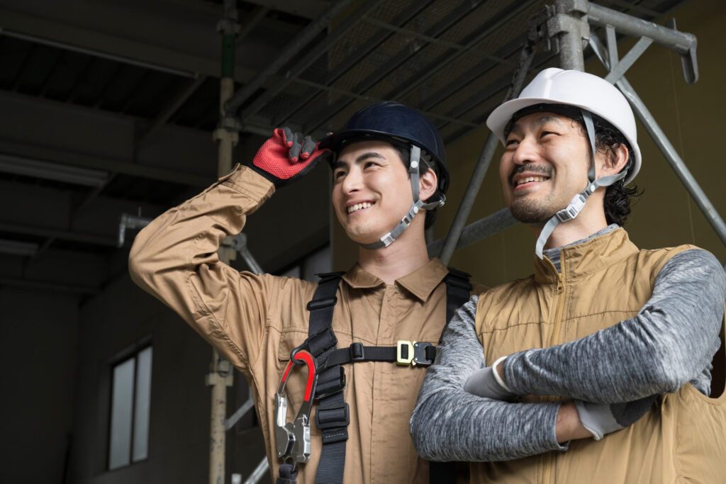 2人で笑顔で並ぶ建築作業をする職人